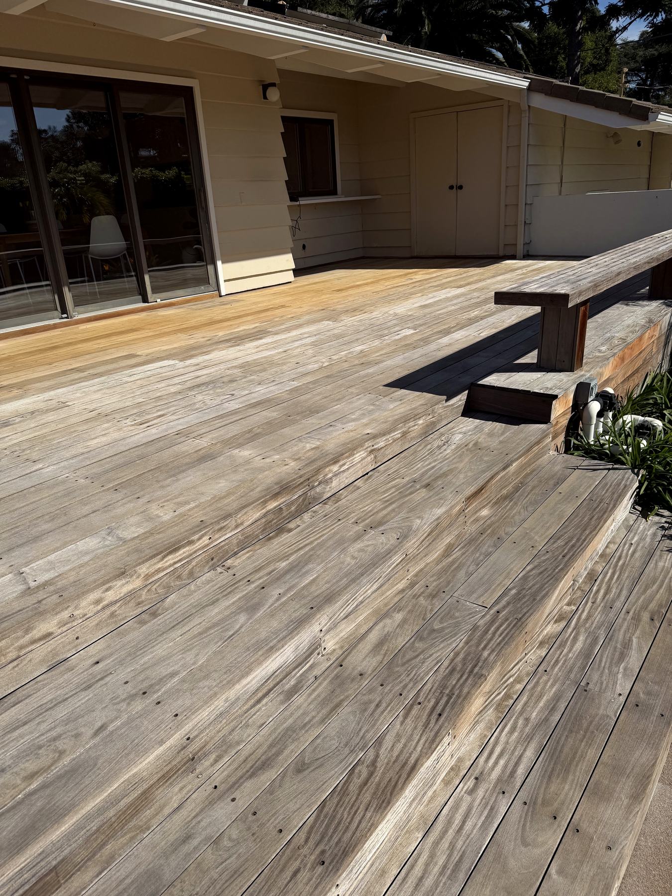 A deck mid-restoration, weathered grey boards beside freshly restored ones.
