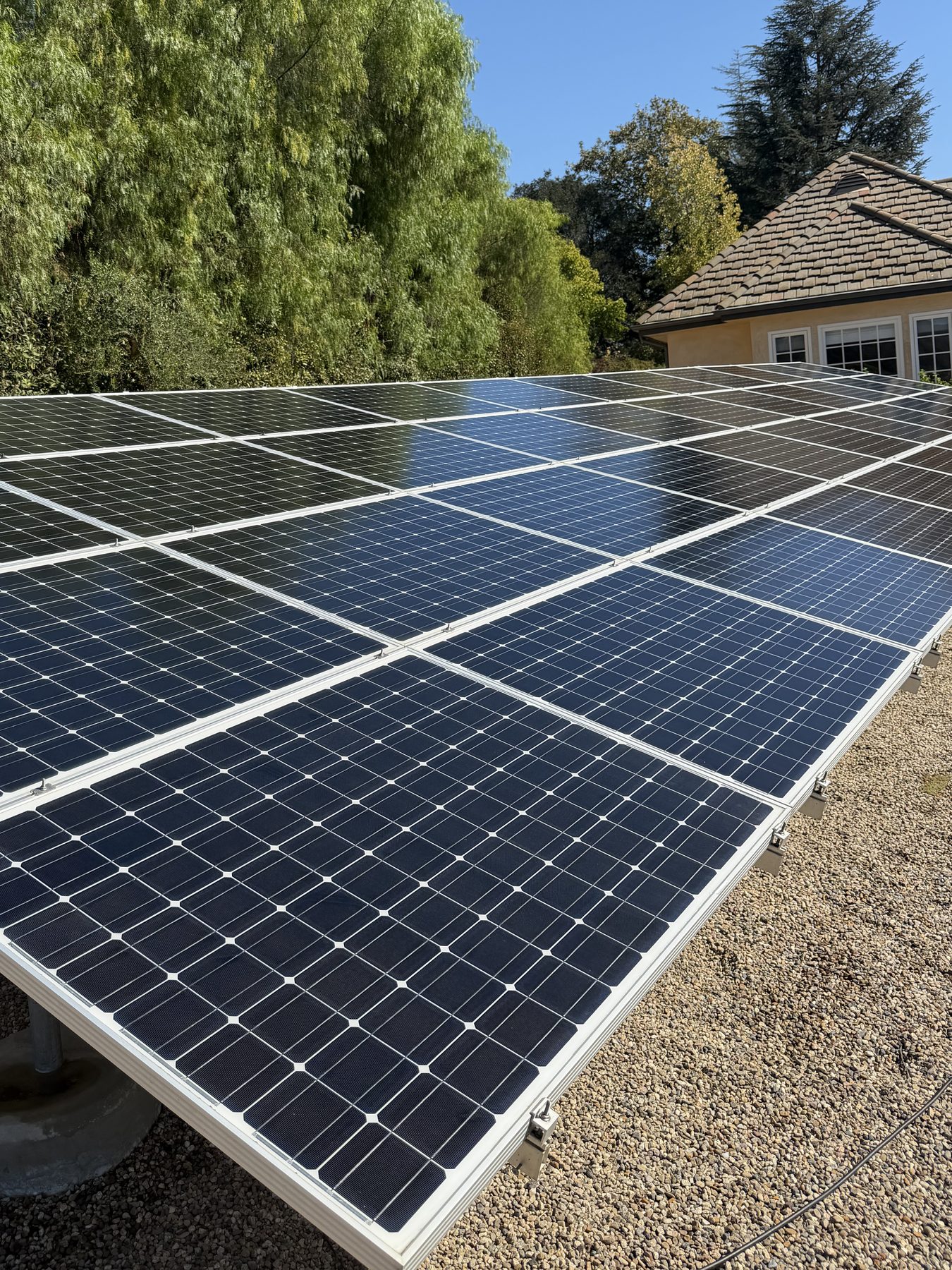 A ground-mounted solar array in the Ojai Valley after cleaning, the panels deep blue and reflecting the sky.